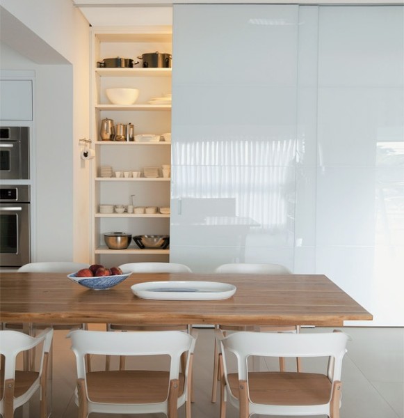 cozinha com mesa de madeira e armarios brancos